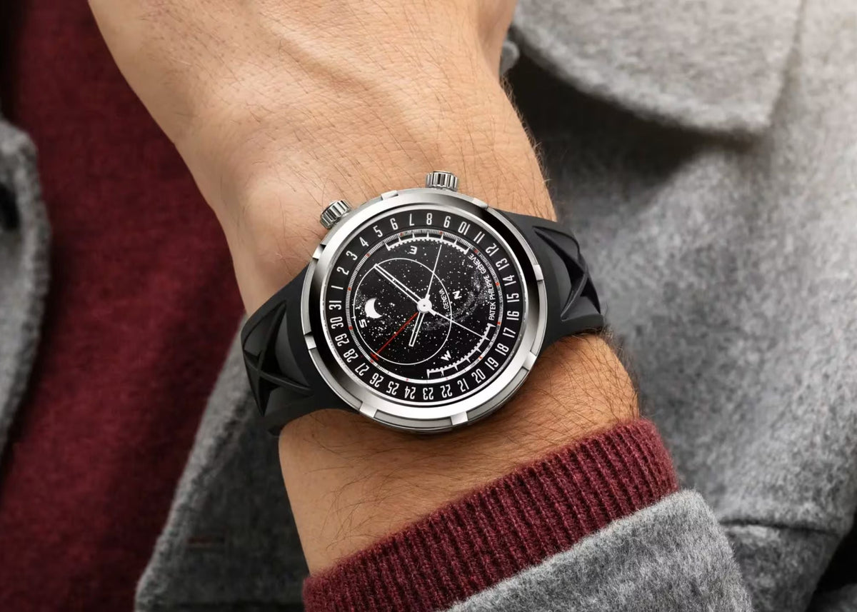 Patek Philippe watch with celestial dial and moon phase, steel case and black leather strap, on the wrist.
